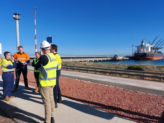 Photo of Kwinana Bulk Terminal, with staff in high visibility jackets and vests in the foreground.