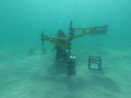 Underwater photo of researcher with apparatus mounted in sand.