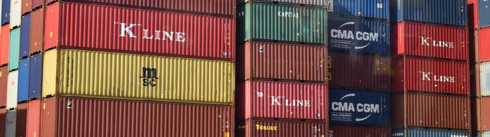 Vertical stacks of shipping containers of shipping containers all grouped together. 