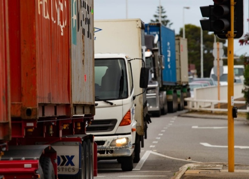Several container trucks in congested traffic driving towards our point of view.