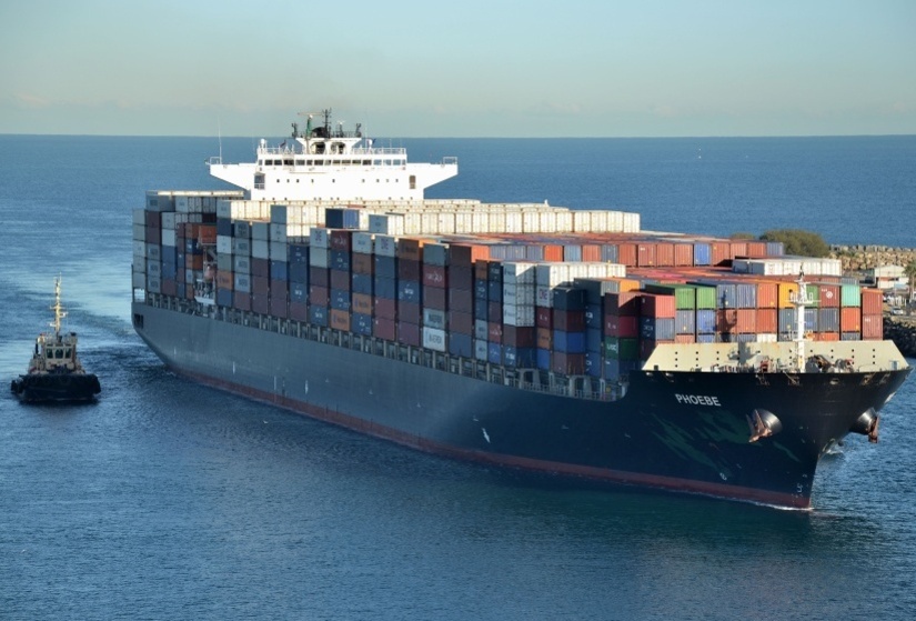 Photo of loaded container ship, alongside smaller vessel.