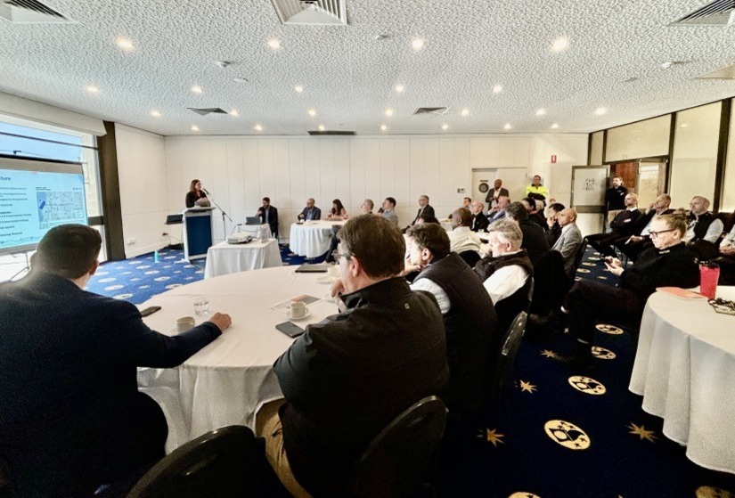 Photo of a conference room full of people during a presentation.