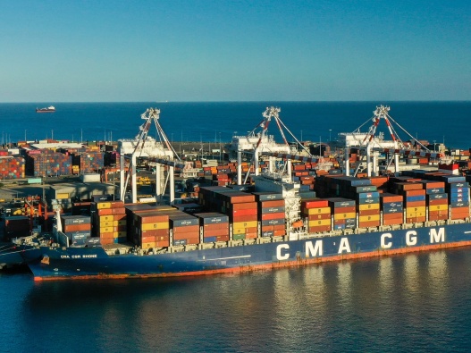 Aerial photo of a container ship underneath ship-to-shore cranes.