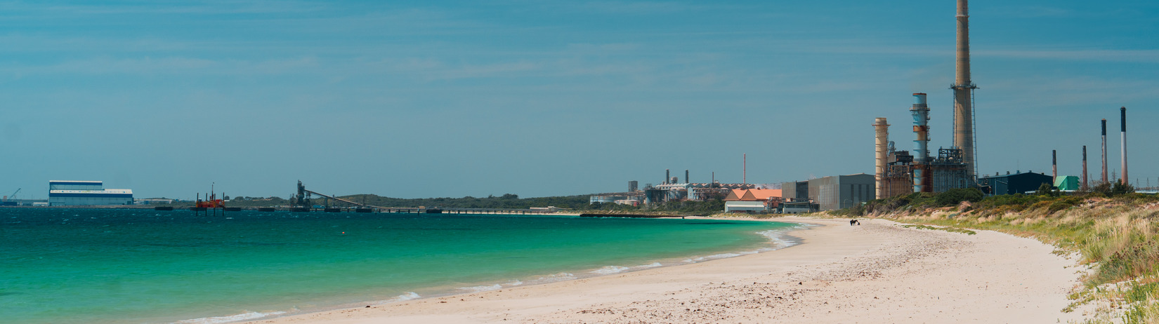 Two horses being led by a rider on to a horse beach.