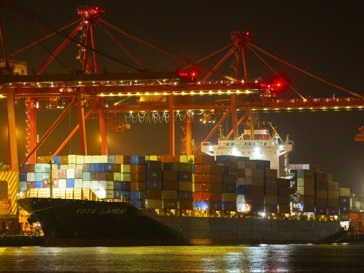 Photo of loaded container ship under lights at night.
