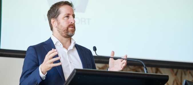 Photo of Patrick Seares standing behind a lectern presenting at a conference.