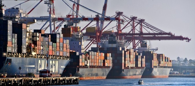 Four container ships at berths beneath ship-to-shore cranes.